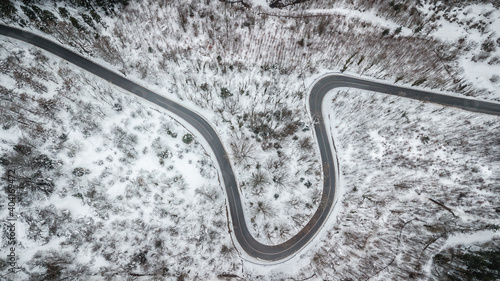 aerial view of alpine road crossing a forest