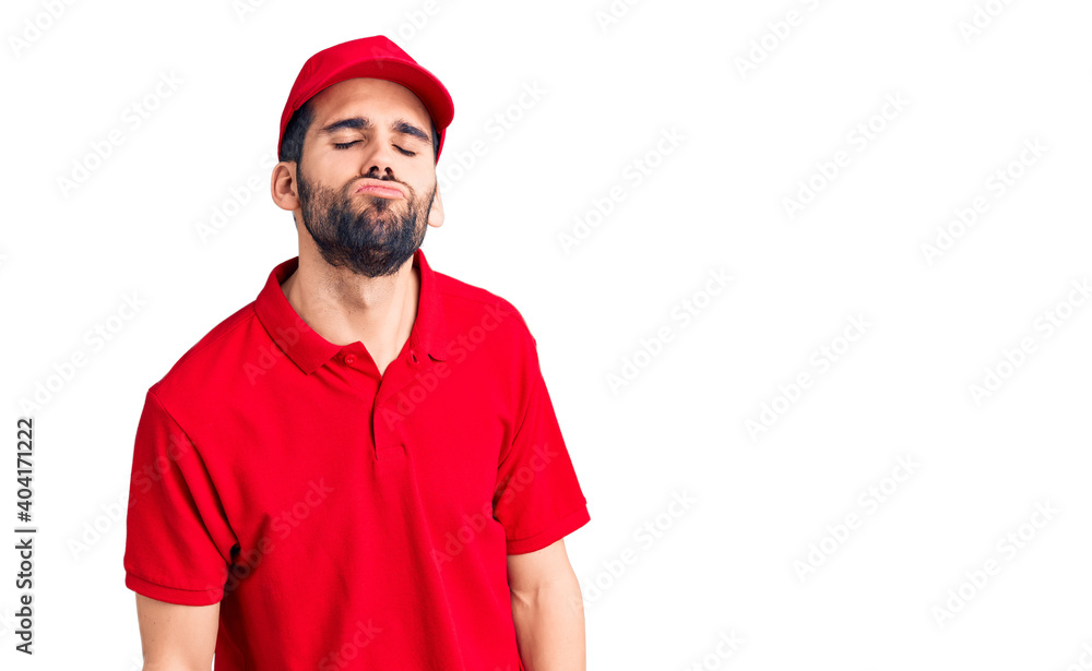 Young handsome man with beard wearing delivery uniform looking at the camera blowing a kiss on air being lovely and sexy. love expression.