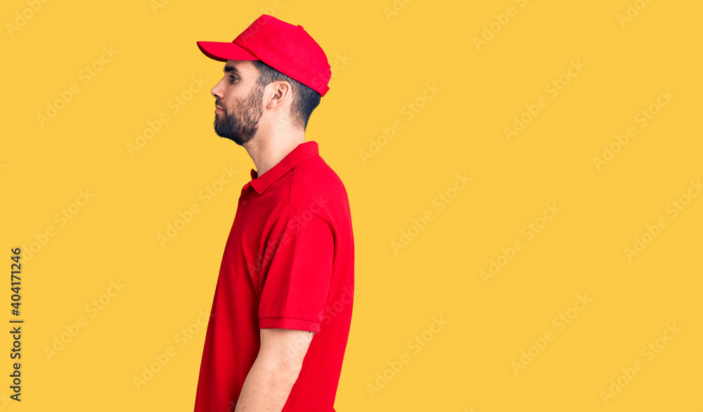 Young handsome man with beard wearing delivery uniform looking to side, relax profile pose with natural face and confident smile. Young handsome man with beard wearing delivery uniform looking to side, relax profile pose with natural face and confident smile.