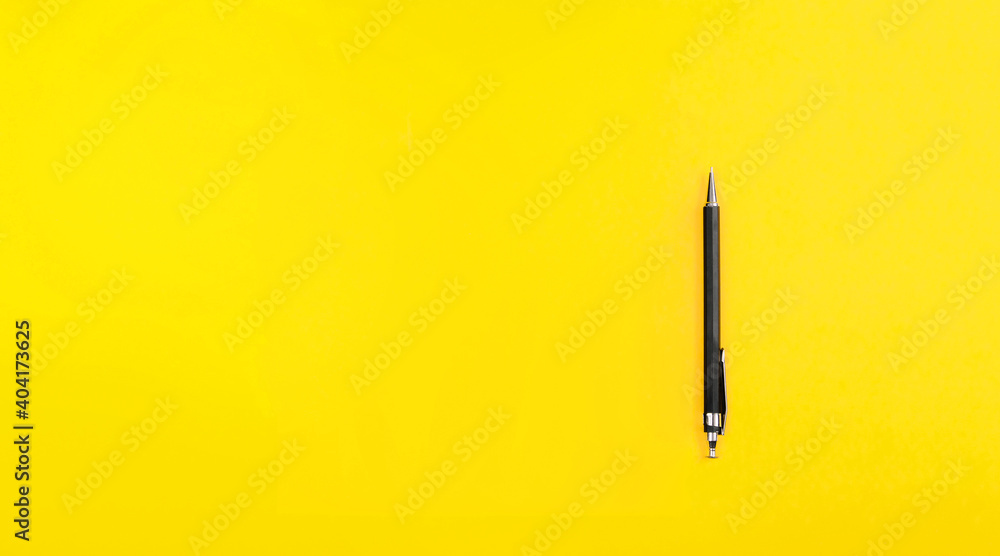 Black metal nib ballpoint pen on yellow background with copy space text ...