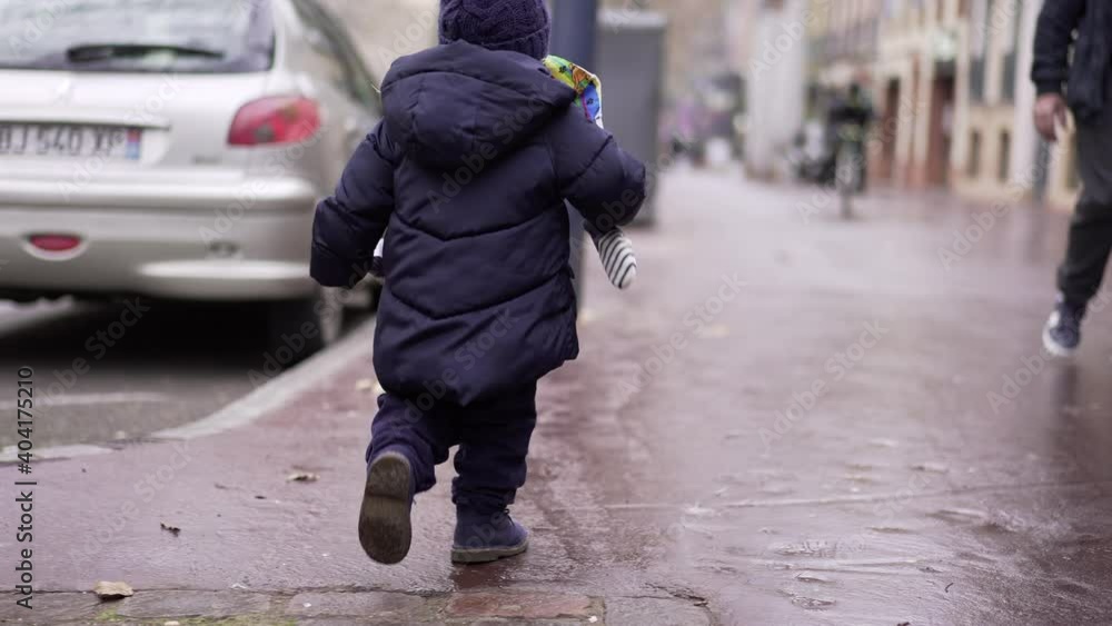 Little toddler running outside in street during winter time Little toddler running outside in street during winter time