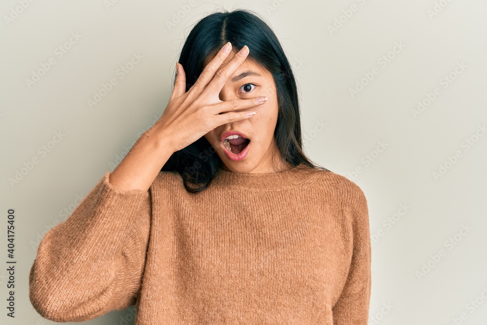 Young chinese woman wearing casual clothes peeking in shock covering face and eyes with hand, looking through fingers afraid Young chinese woman wearing casual clothes peeking in shock covering face and eyes with hand, looking through fingers afraid