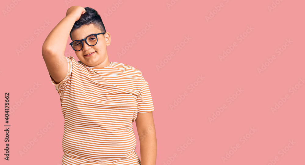 Little boy kid wearing casual clothes and glasses smiling confident touching hair with hand up gesture, posing attractive and fashionable Little boy kid wearing casual clothes and glasses smiling confident touching hair with hand up gesture, posing attractive and fashionable