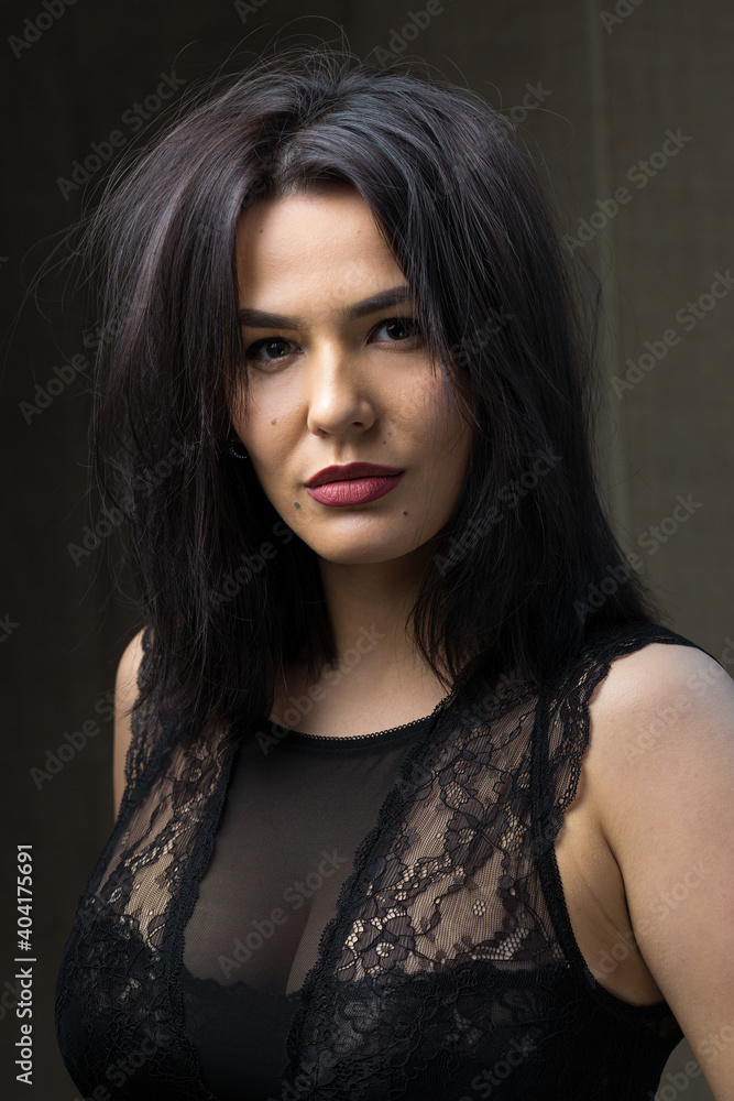 Fototapeta premium Portrait of a young sexy brunette girl in a lace top in dramatic tones. Vintage photo.