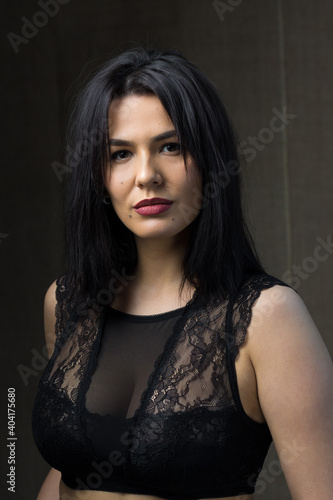 Portrait of a young sexy brunette girl in a lace top in dramatic tones. Vintage photo.