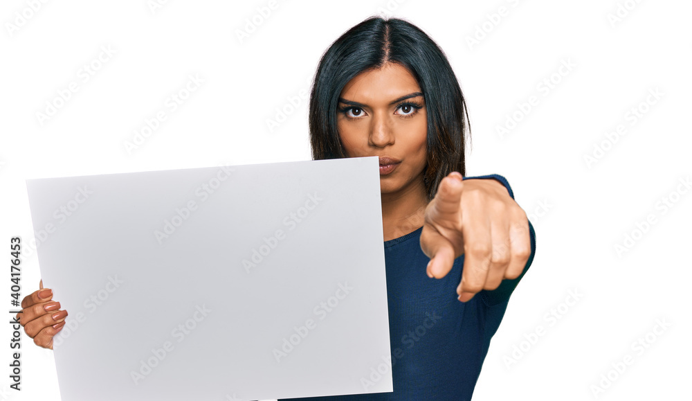 Young latin transsexual transgender woman holding blank empty banner pointing with finger to the camera and to you, confident gesture looking serious Young latin transsexual transgender woman holding blank empty banner pointing with finger to the camera and to you, confident gesture looking serious