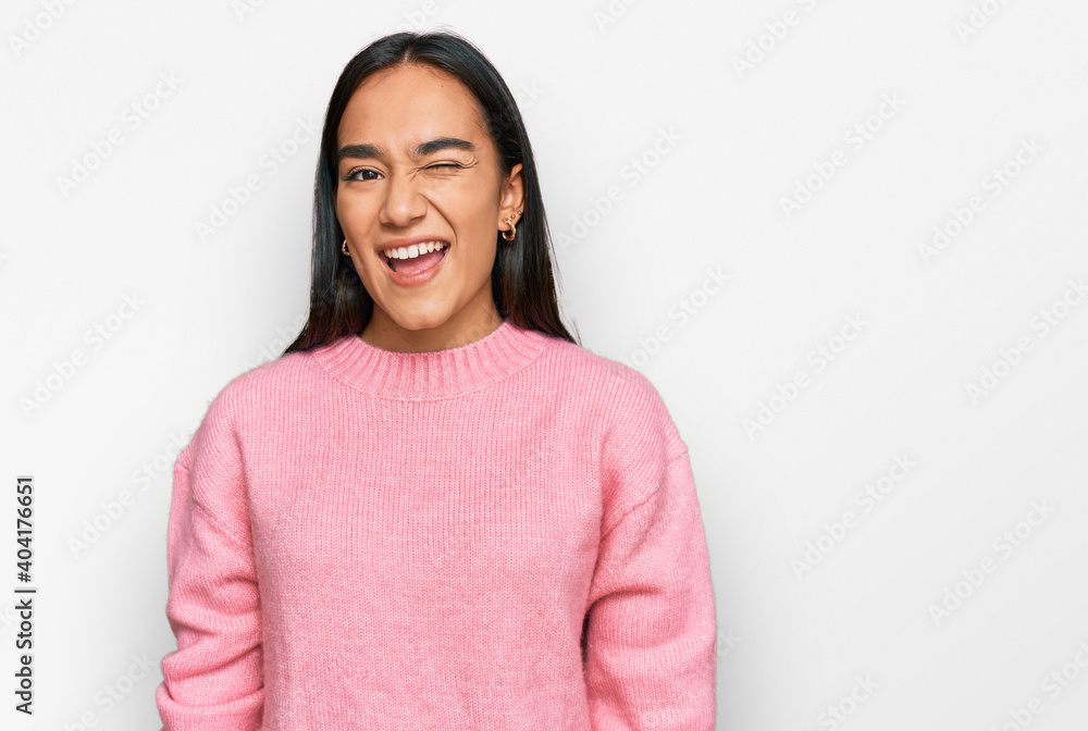 Young asian woman wearing casual winter sweater winking looking at the camera with sexy expression, cheerful and happy face. Young asian woman wearing casual winter sweater winking looking at the camera with sexy expression, cheerful and happy face.