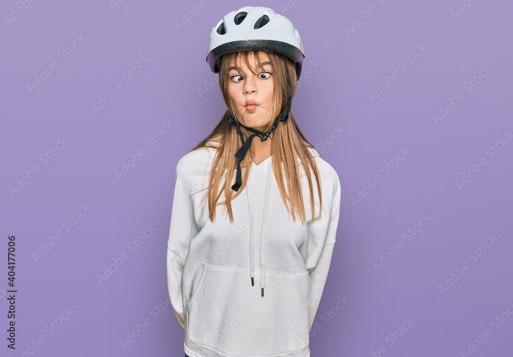 Teenager caucasian girl wearing bike helmet making fish face with lips, crazy and comical gesture. funny expression. Teenager caucasian girl wearing bike helmet making fish face with lips, crazy and comical gesture. funny expression.