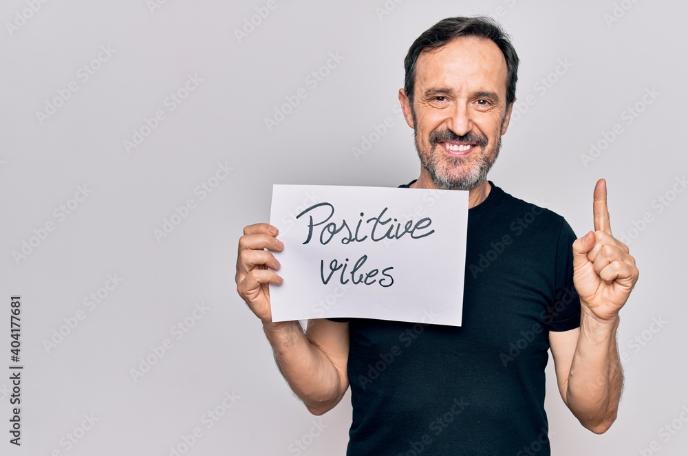 Middle age handosme man asking for good attitude holding paper with positive vibes message smiling with an idea or question pointing finger with happy face, number one Middle age handosme man asking for good attitude holding paper with positive vibes message smiling with an idea or question pointing finger with happy face, number one