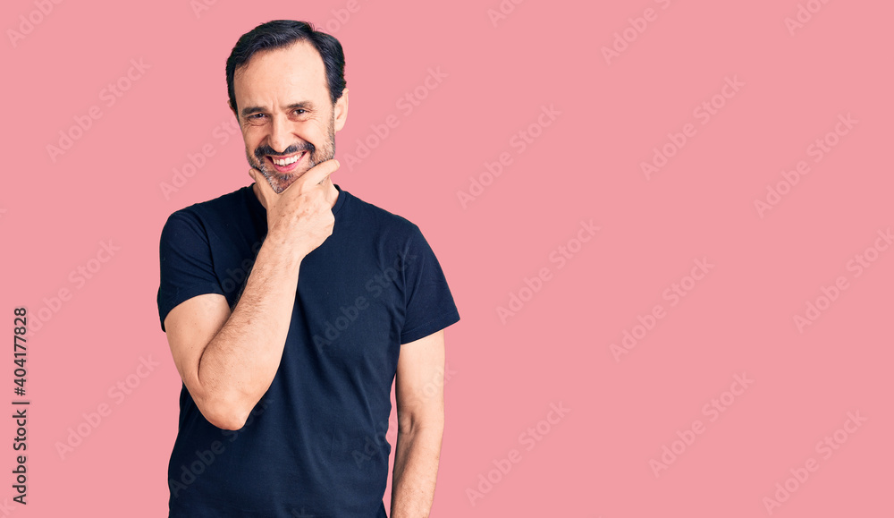 Middle age handsome man wearing casual t-shirt looking confident at the camera smiling with crossed arms and hand raised on chin. thinking positive. Middle age handsome man wearing casual t-shirt looking confident at the camera smiling with crossed arms and hand raised on chin. thinking positive.