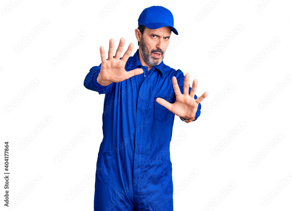 Middle age handsome man wearing mechanic uniform doing stop gesture with hands palms, angry and frustration expression Middle age handsome man wearing mechanic uniform doing stop gesture with hands palms, angry and frustration expression