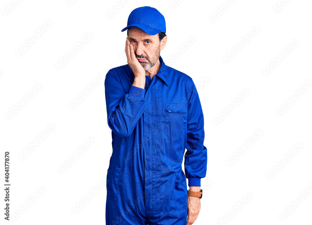 Middle age handsome man wearing mechanic uniform thinking looking tired and bored with depression problems with crossed arms.