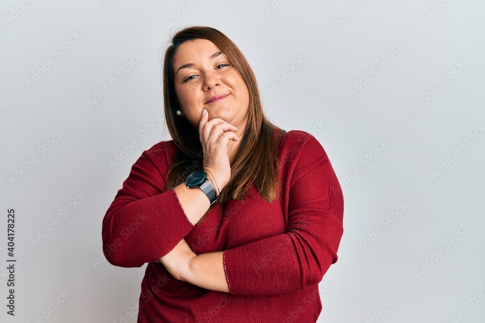 Beautiful brunette plus size woman wearing casual clothes smiling looking confident at the camera with crossed arms and hand on chin. thinking positive. Beautiful brunette plus size woman wearing casual clothes smiling looking confident at the camera with crossed arms and hand on chin. thinking positive.