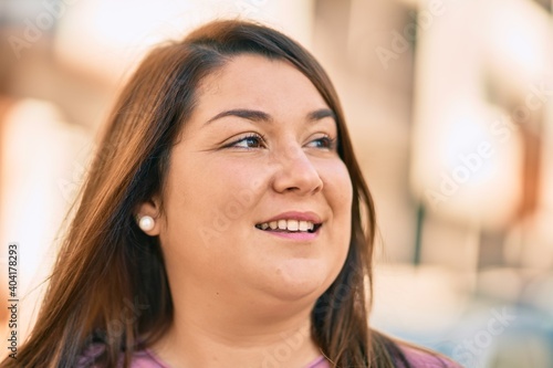 Young hispanic plus size woman smiling happy standing at the city.