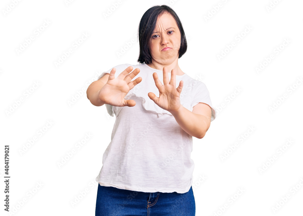 Brunette woman with down syndrome wearing casual white tshirt moving away hands palms showing refusal and denial with afraid and disgusting expression. stop and forbidden. Brunette woman with down syndrome wearing casual white tshirt moving away hands palms showing refusal and denial with afraid and disgusting expression. stop and forbidden.