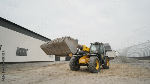 Tractor moves rubble to truck. Excavator-loader rakes rubble from pile at construction site and loads dump truck. Clearing site