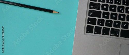 notebook and pencil on a turquoise desk