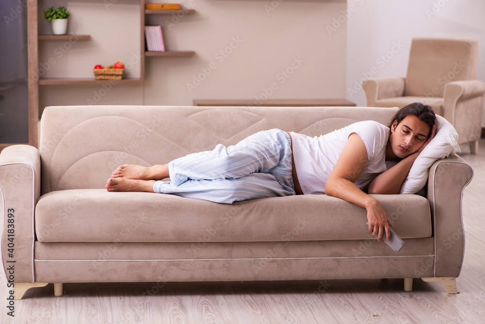 Young lazy man in oversleeping concept at home Young lazy man in oversleeping concept at home