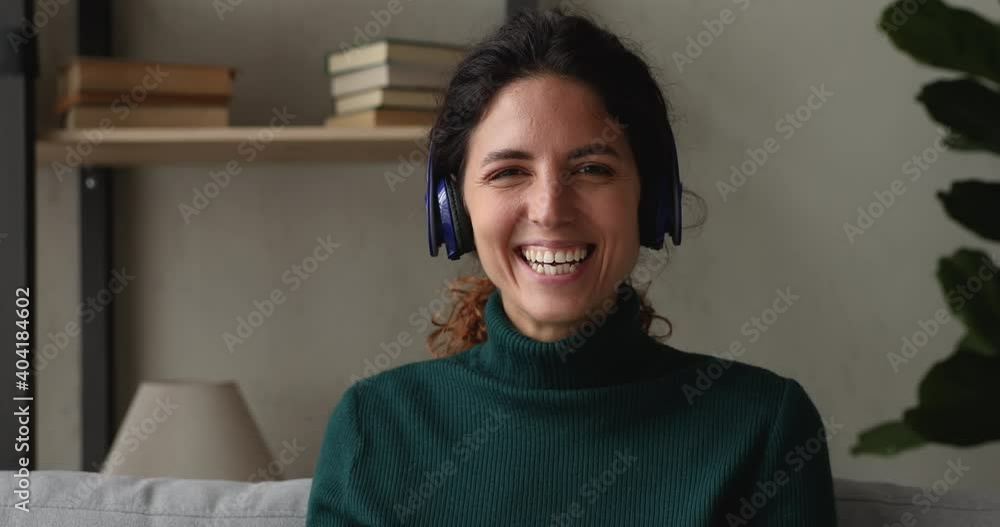 Head shot portrait happy woman sit on sofa in living room looks at camera wave hand greeting friend start conversation by videocall. Vlogger develop channel make livestream, video call event concept Head shot portrait happy woman sit on sofa in living room looks at camera wave hand greeting friend start conversation by videocall. Vlogger develop channel make livestream, video call event concept