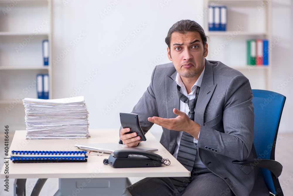 Young male bookkeeper calculating expences Young male bookkeeper calculating expences