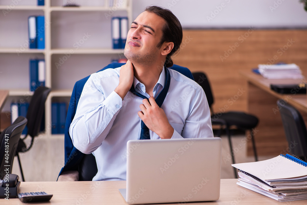 Young male employee suffering from osteochondrosis at workplace Young male employee suffering from osteochondrosis at workplace