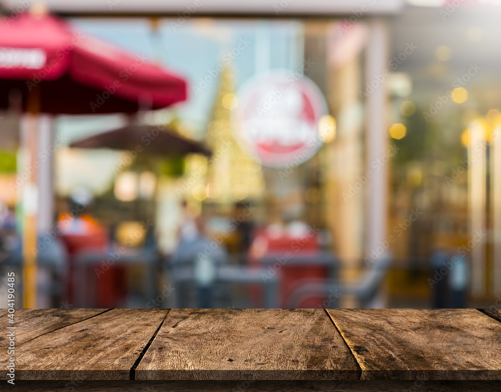 Brown wood table in front of a cafe blurred background with bokeh lights.
