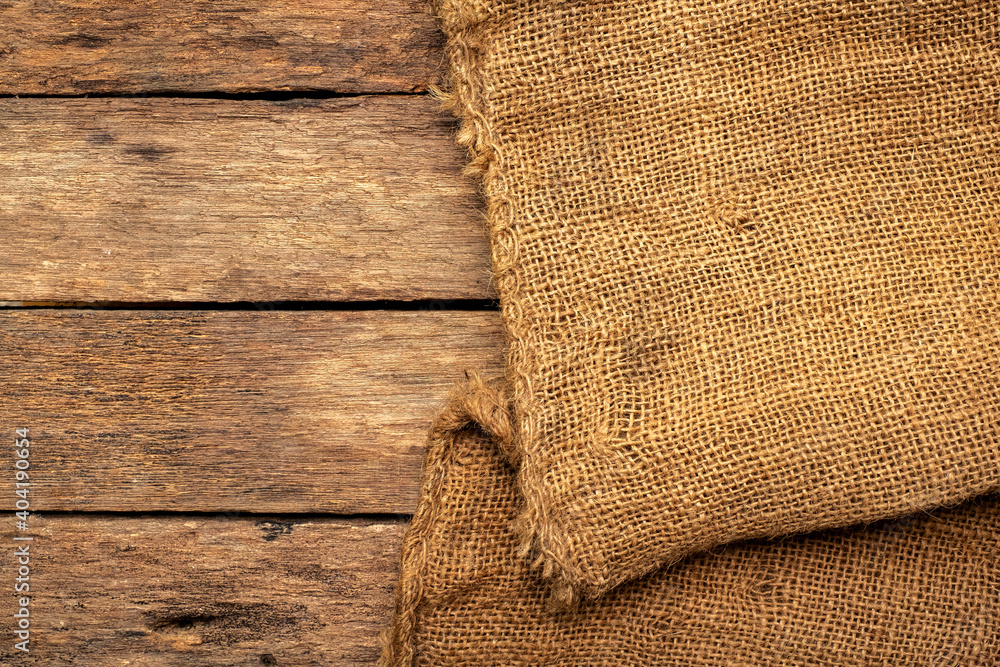 Brown burlap cloth background or sack cloth for packing on brown wood panel Brown burlap cloth background or sack cloth for packing on brown wood panel