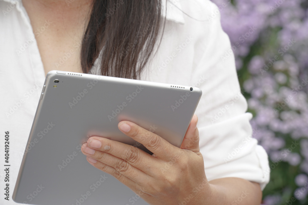 Tablet in the hands of a women,Scientist observing Purple flowers plants. Tablet in the hands of a women,Scientist observing Purple flowers plants.