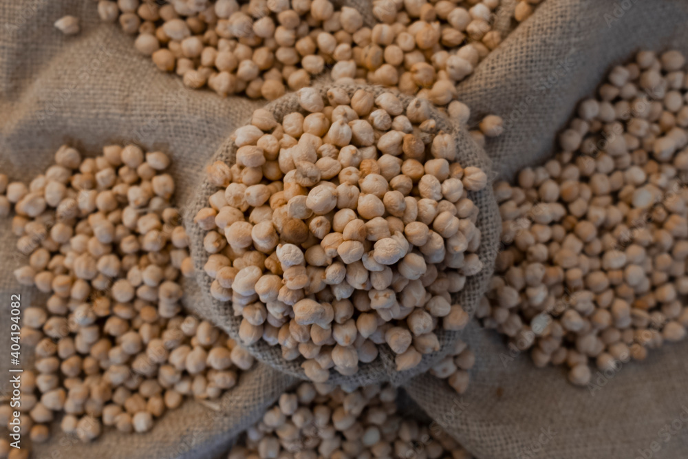 top view of chickpea in antique sack. Uncooked Dry chickpeas in sack isolated on burlap background. Grains are scattered out of the bag. Heap of legume chickpeas background with sackcloth top view of chickpea in antique sack. Uncooked Dry chickpeas in sack isolated on burlap background. Grains are scattered out of the bag. Heap of legume chickpeas background with sackcloth
