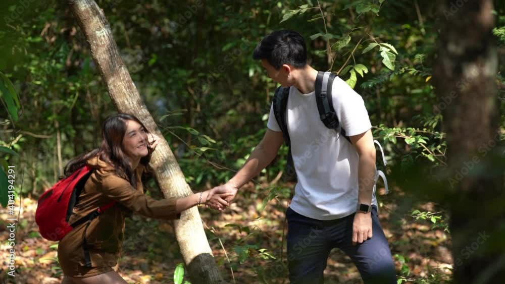 Smiling Asian couple holding hands hiking and climbing together on mountain hill. Happy man and woman relax and enjoy travel and summer outdoor lifestyle with beautiful nature on holiday vacation. Smiling Asian couple holding hands hiking and climbing together on mountain hill. Happy man and woman relax and enjoy travel and summer outdoor lifestyle with beautiful nature on holiday vacation.