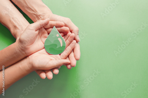 Hands holding paper cut green oil drop, CSR, alternative biofuel, algae fuel, renewable green energy, sustainable concept  