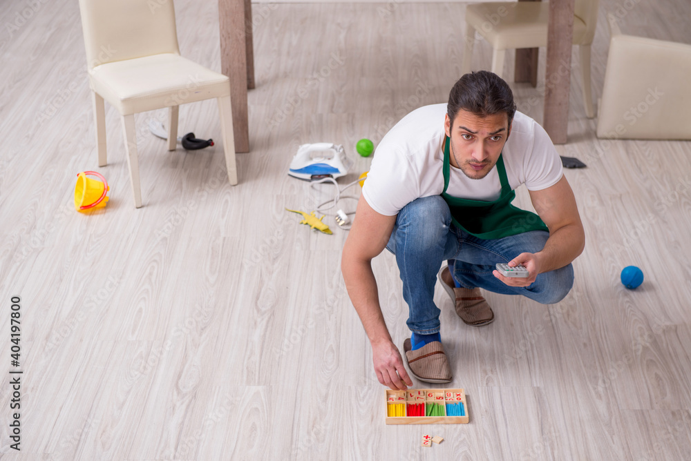 Young male contractor cleaning the flat after kids' party Young male contractor cleaning the flat after kids' party