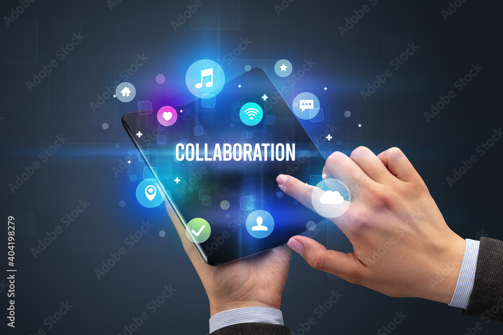 Businessman holding a foldable smartphone with COLLABORATION inscription, social media concept Businessman holding a foldable smartphone with COLLABORATION inscription, social media concept