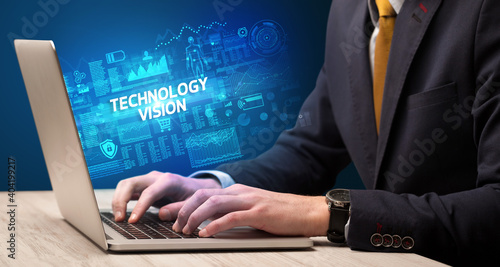 Businessman working on laptop with TECHNOLOGY VISION inscription, cyber technology concept
