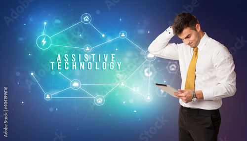 Businessman in front of cloud service icons with ASSISTIVE TECHNOLOGY inscription, modern technology concept