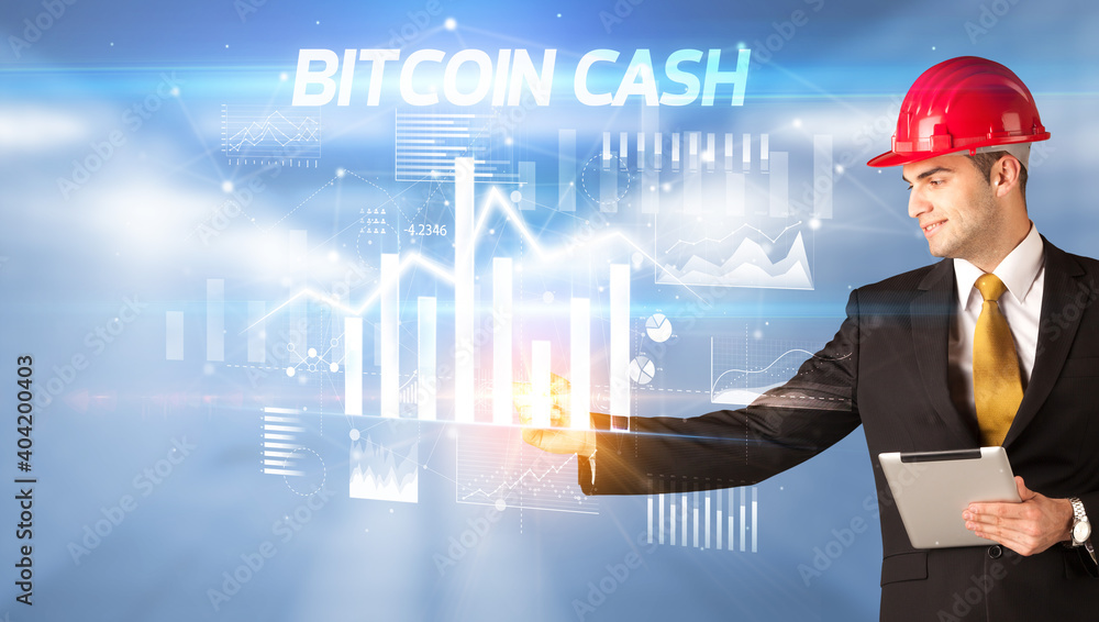 Handsome businessman with helmet drawing BITCOIN CASH inscription, architecture business plan concept Handsome businessman with helmet drawing BITCOIN CASH inscription, architecture business plan concept