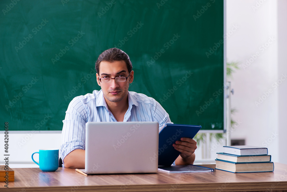 Young male teacher in front of blackboard Young male teacher in front of blackboard
