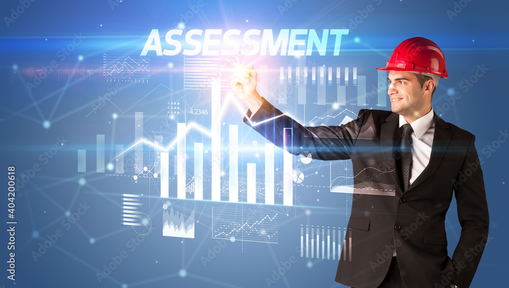 Handsome businessman with helmet drawing ASSESSMENT inscription, architecture business plan concept Handsome businessman with helmet drawing ASSESSMENT inscription, architecture business plan concept