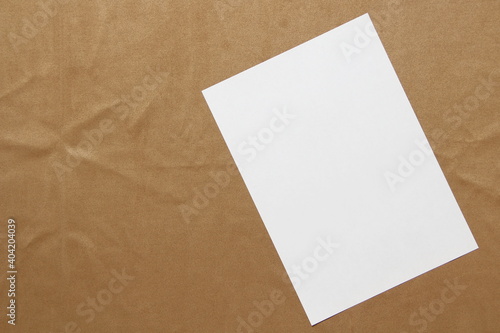 Template of white paper lies diagonally on light brown cloth background. Concept of business plan and strategy. Stock photo with empty space for text and design.