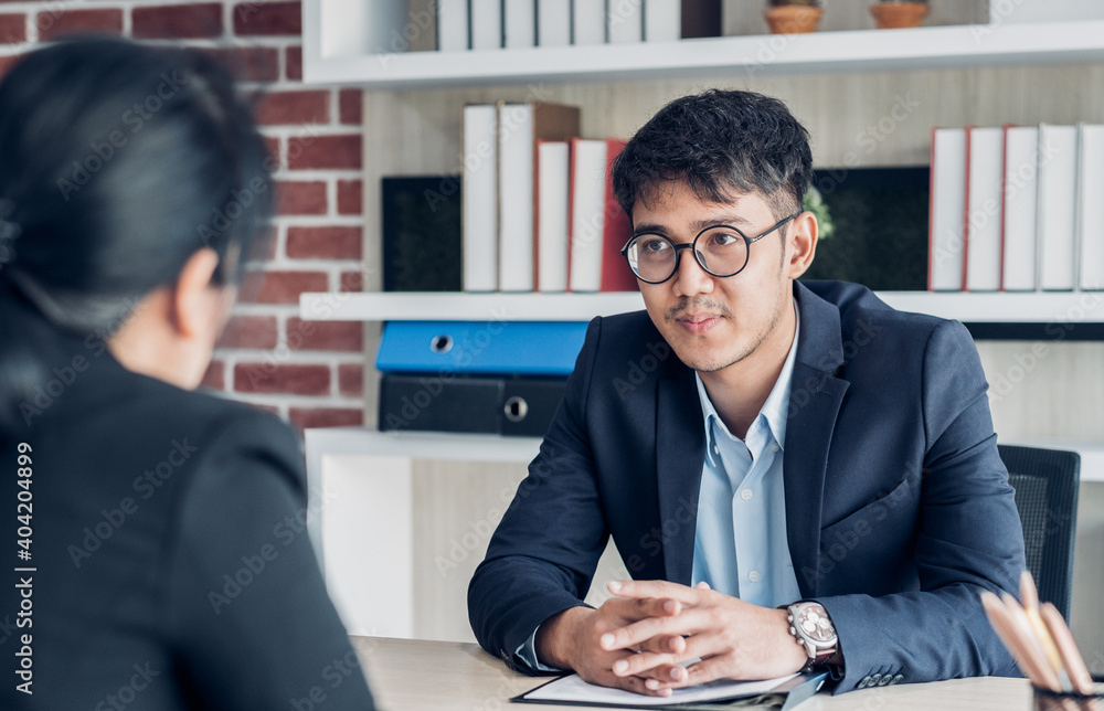 young asian businessman and businesswoman talking about business agreement at meeting table in modern office.business partnership concept.satisfied the deal with client negotiation - obrazy, fototapety, plakaty 