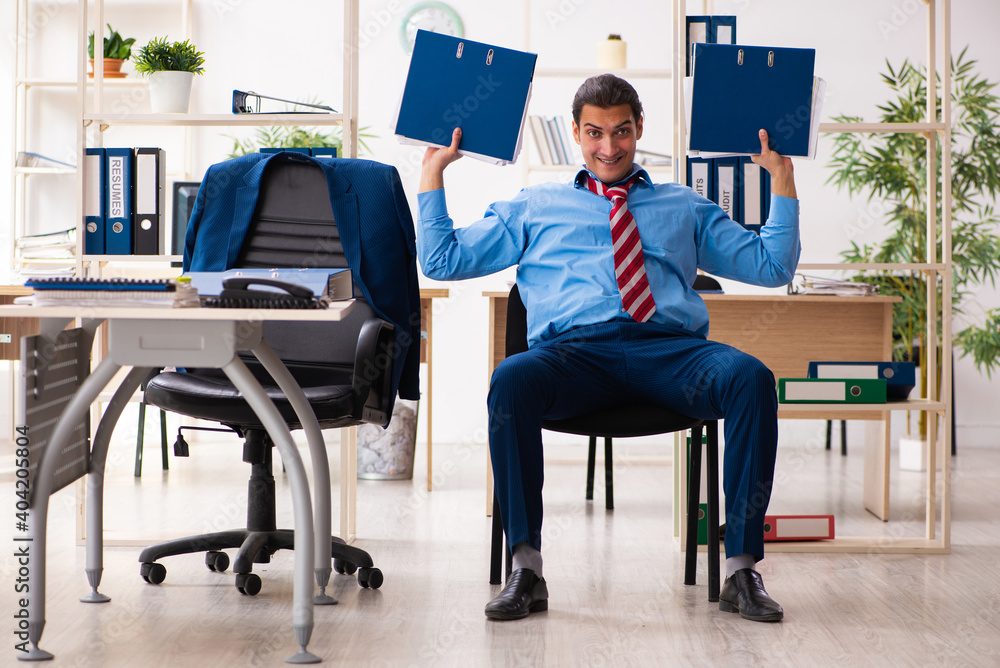Young male employee doing sport exercises at workplace Young male employee doing sport exercises at workplace