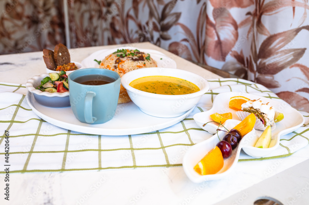 set of dishes for lunch. chicken soup, pilaf with salvt, hot tea and bun set of dishes for lunch. chicken soup, pilaf with salvt, hot tea and bun