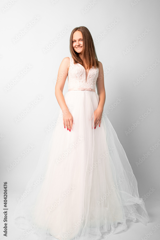 Happy bride. Special wedding day. Festive shooting. Smiling women in white fluffy dress posing on camera in studio isolated on light. Happy bride. Special wedding day. Festive shooting. Smiling women in white fluffy dress posing on camera in studio isolated on light.