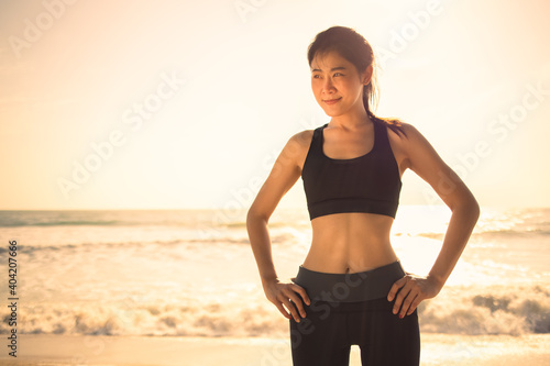 Young Asian athletic muscle woman standing and warmup for running on beach in morning or evening 