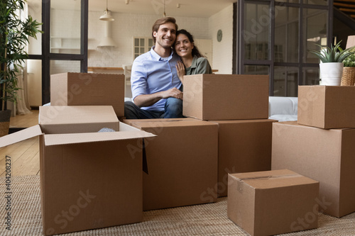 Happy millennial Caucasian couple feel overjoyed unpacking on moving day to new house. Smiling young man and woman renters unbox packages relocate to own apartment or home together. Rent concept.