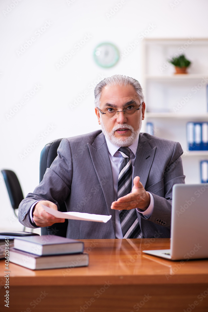 Old male businessman employee reading contract in the office