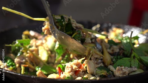 Stir fried spicy fish meat in pan cooking forpeople in restaurant, close up slice of fish and vegetable herb to mixing photo