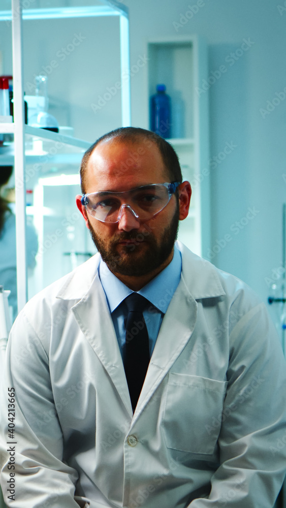 Tired doctor looking exhausted at camera in modern equipped lab late at night. Medical chemist team examining virus evolution using high tech and chemistry tools for research, vaccine development. Tired doctor looking exhausted at camera in modern equipped lab late at night. Medical chemist team examining virus evolution using high tech and chemistry tools for research, vaccine development.