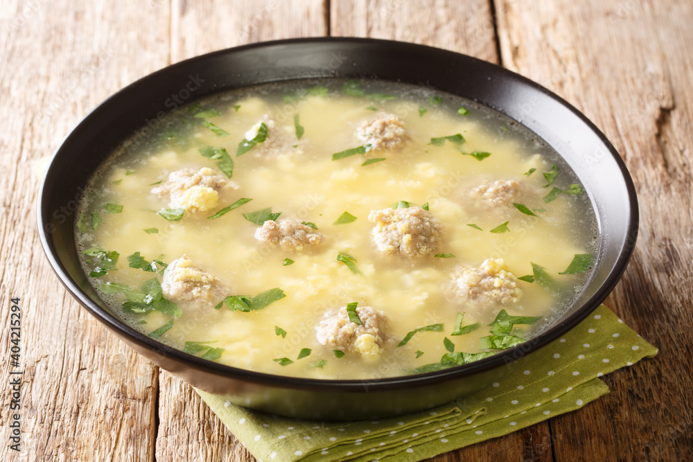 Sciusceddu is a festive Italian soup with the lightest, most tender meatballs in a comforting creamy egg soup closeup in the plate on the table. horizontal
