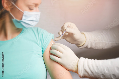 Doctor giving shot or vaccine to a nurse shoulder. Vaccination and prevention against flu or virus pandemic.